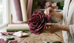 Crafter's hands shaping realistic burgundy crepe paper petals for giant flowers